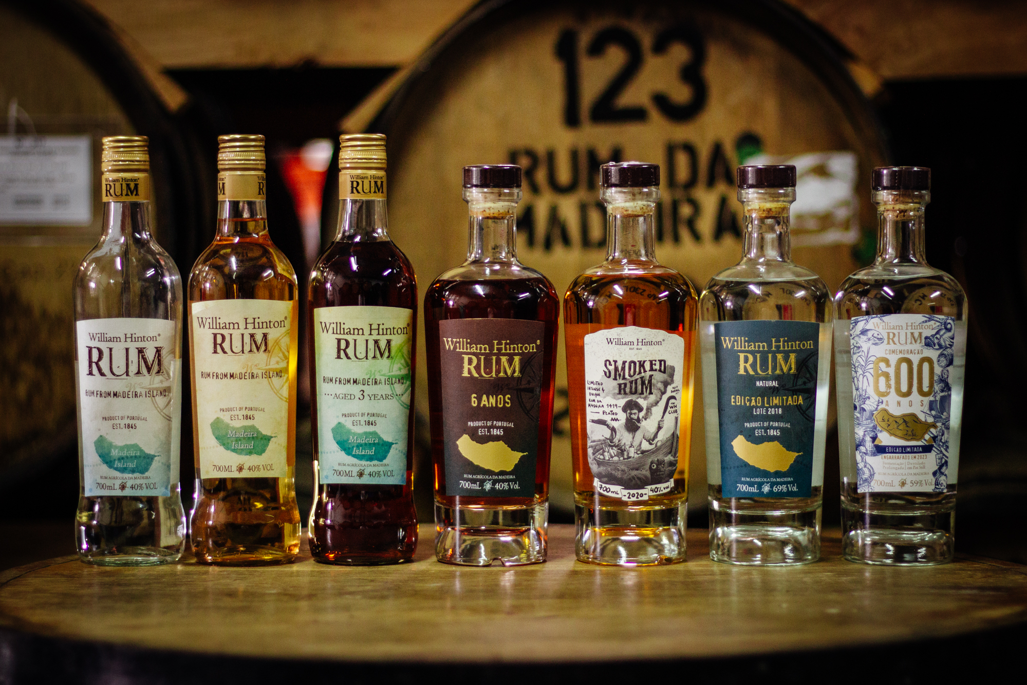 Selection of William Hinton rums displayed in front of ageing casks.